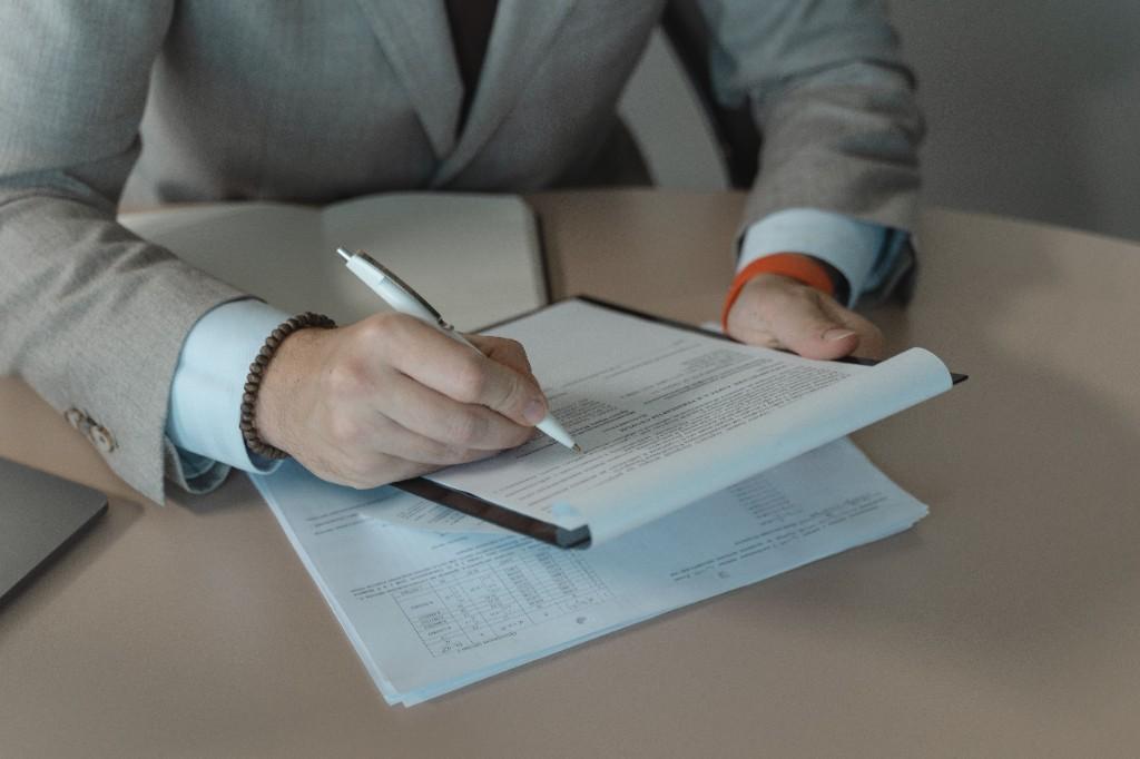 Professional reviewing case documents on a clipboard at a desk with data tables and notes